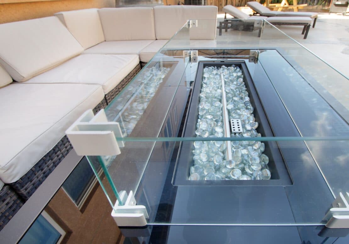 Gas firepit table with fire glass and a glass wind guard