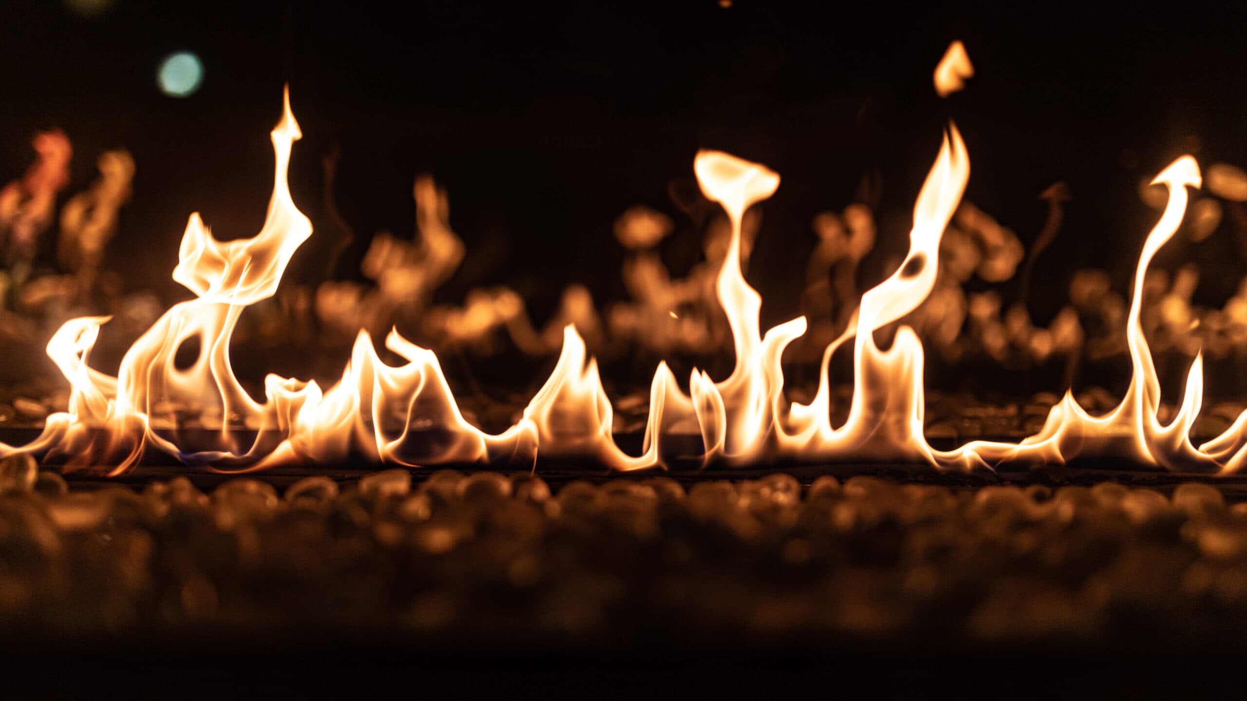 Row of flames over a bed of pebbles in a linear gas fireplace