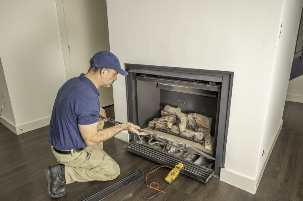 Technician testing an open gas fireplace with a multimeter