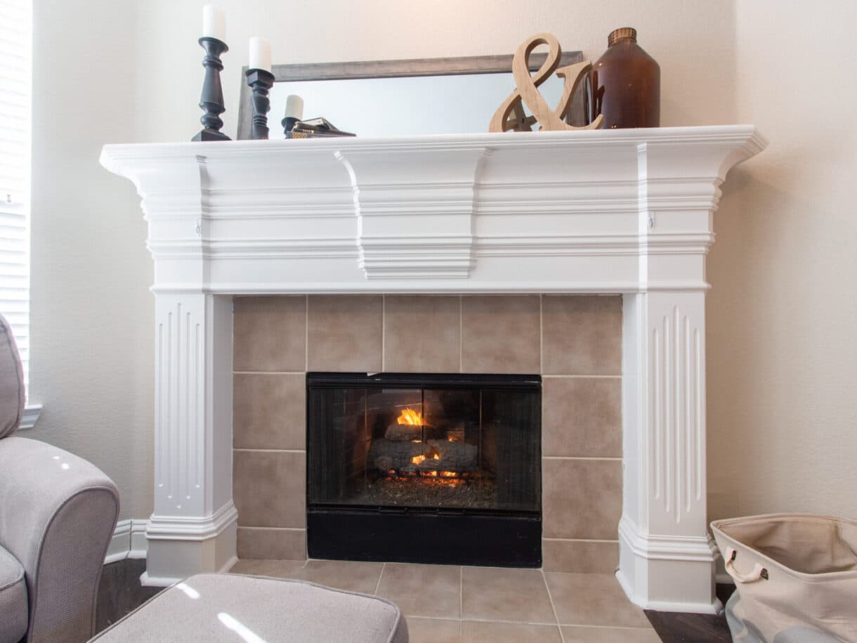 Gas fireplace alight under a white painted mantel