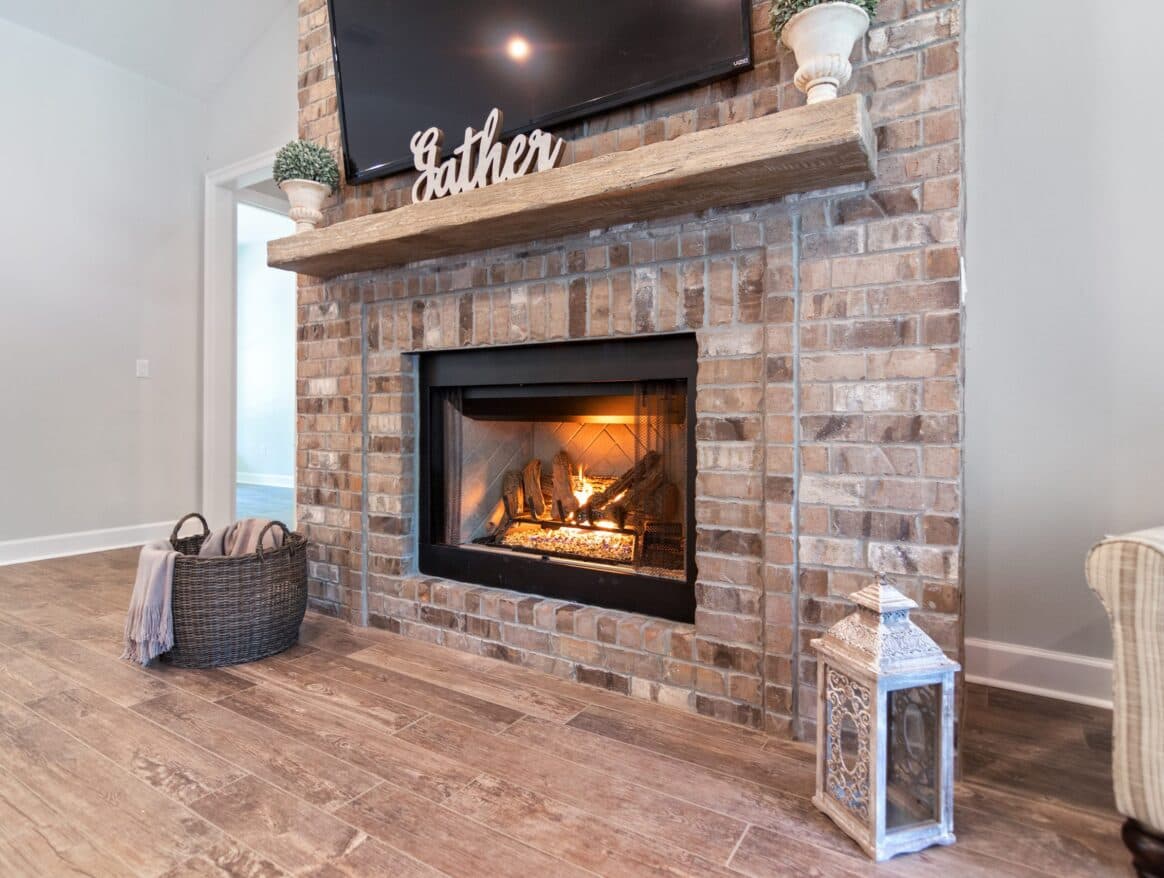 Brick gas fireplace with a reclaimed timber mantel