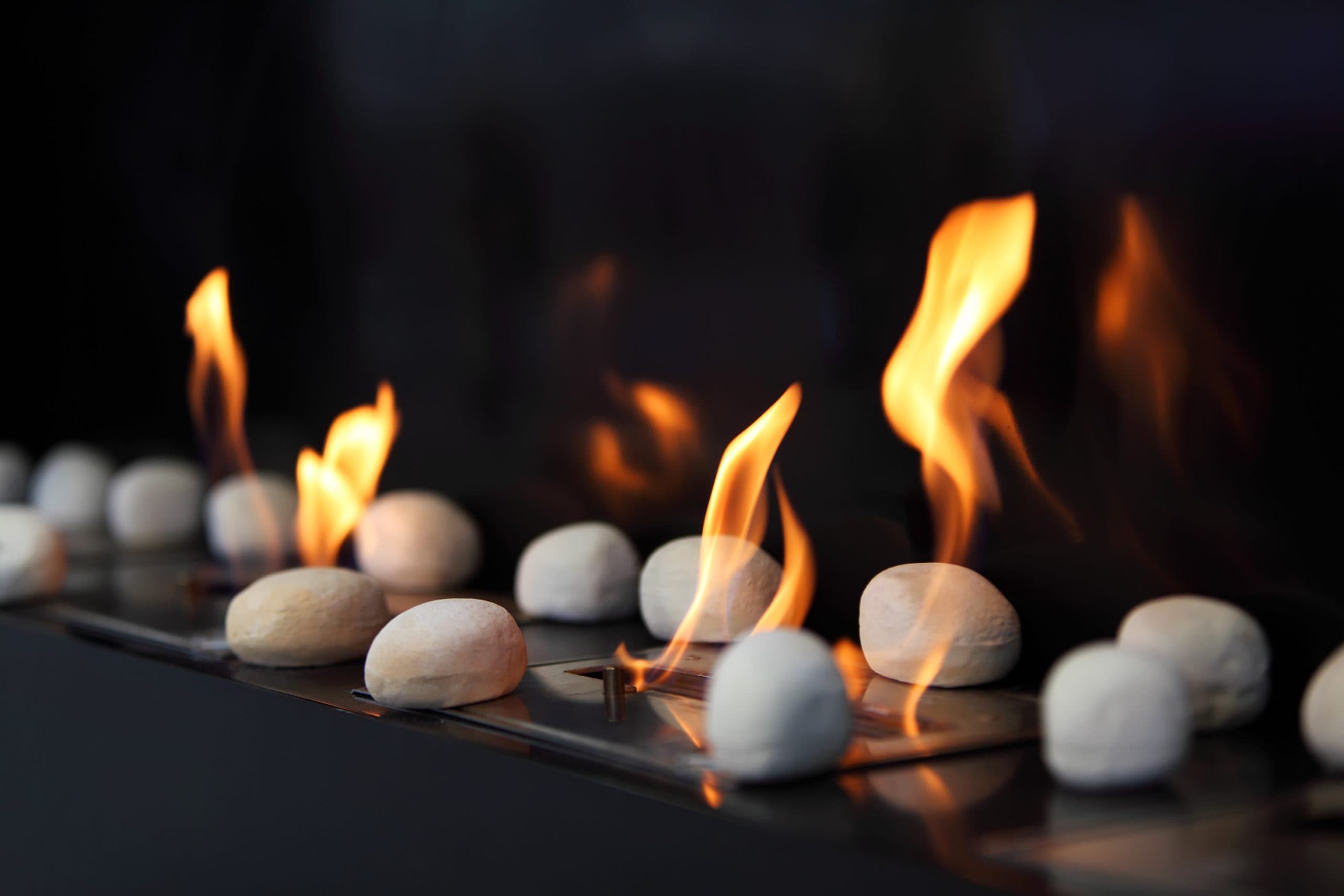 Flames rising between white stones on a gas fireplace burner